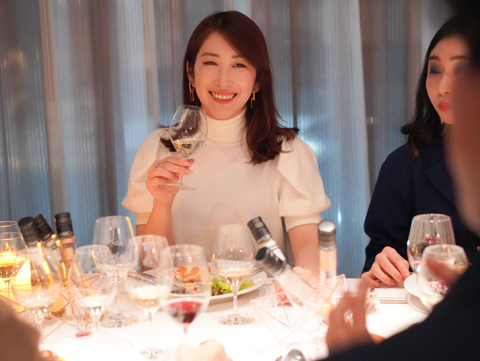 ワイングラスを持つ女性の笑顔のディナーシーン